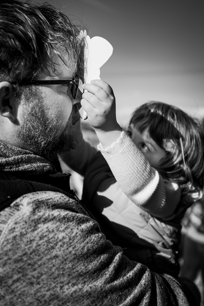 A girl held by his father putting a mask in front of his face.