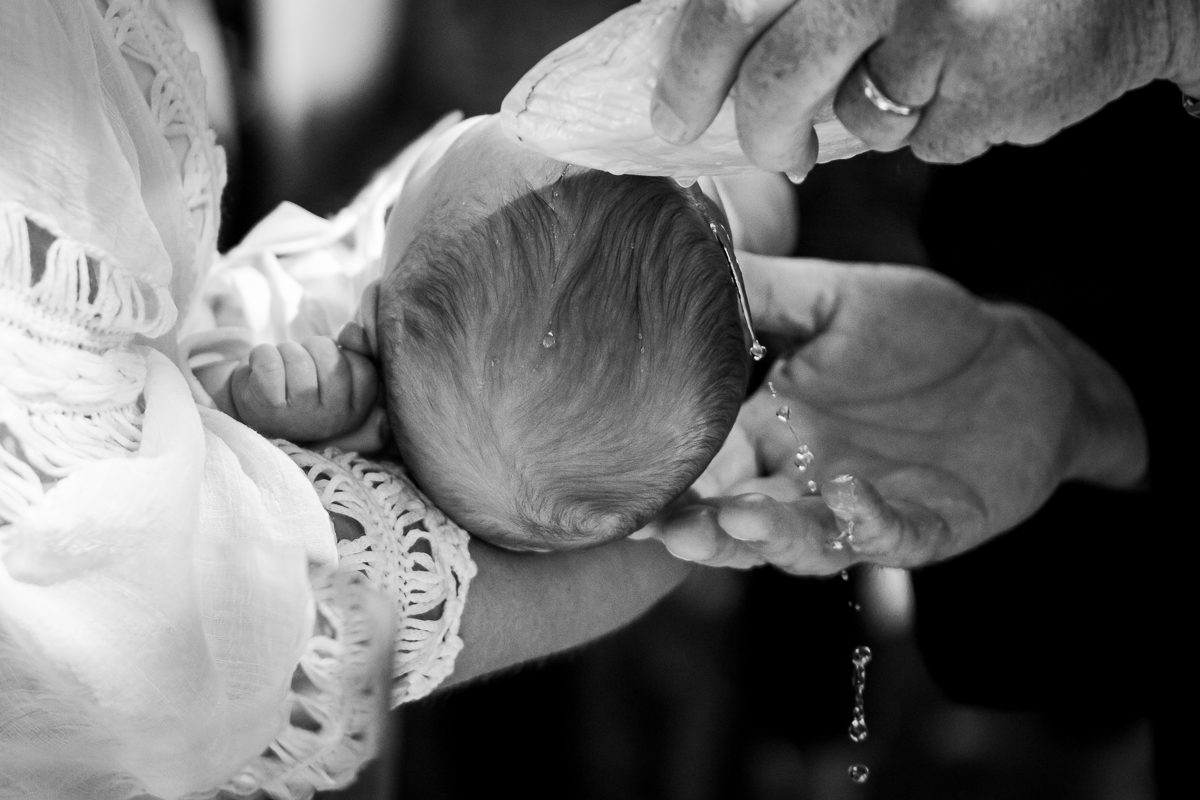 Water being dropped on a baby's head during a christening.