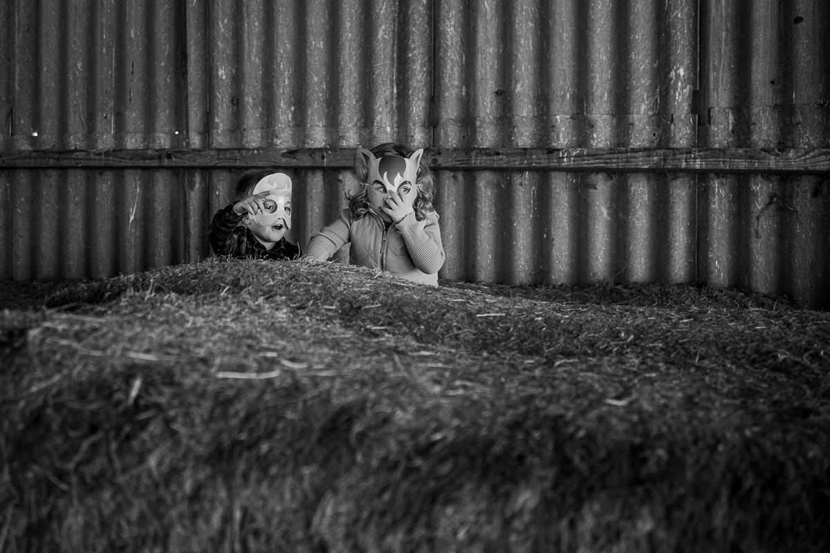 A young boy and girl wearing animal masks standing in a play barn.